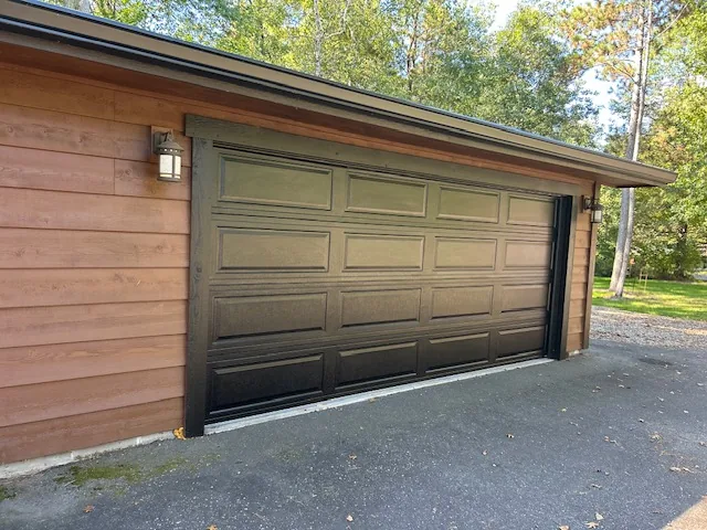 Black panel garage door on a cedar-sided home